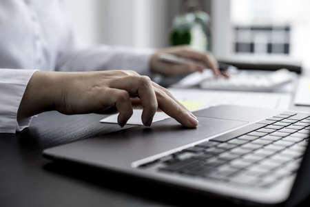 A close-up businesswoman using her laptop's touchpad, using her laptop to search the Internet and chat with friends and business partners using a messaging program. Concept of technology.の写真素材