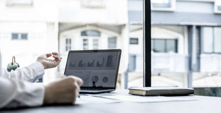 A businesswoman pointing at a laptop screen that opens the company's annual financial summary is examining the document together with the head of the finance department that made it. Financial conceptの写真素材
