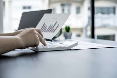 The head sales department checks the monthly sales datasheet for the salesperson to calculate the monthly commission, she looks at the document and presses the calculator. Sales management conceptの写真素材