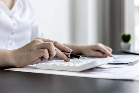 The head sales department checks the monthly sales datasheet for the salesperson to calculate the monthly commission, she looks at the document and presses the calculator. Sales management conceptの写真素材