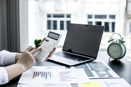 The head sales department checks the monthly sales datasheet for the salesperson to calculate the monthly commission, she looks at the document and presses the calculator. Sales management conceptの写真素材
