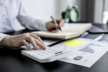 The head sales department checks the monthly sales datasheet for the salesperson to calculate the monthly commission, she looks at the document and presses the calculator. Sales management conceptの写真素材