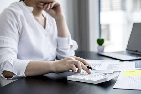Top view woman holding a smartphone and using a laptop uses a smartphone. Chat with friends through instant messaging to discuss business together and use your laptop to find information on the web.の写真素材