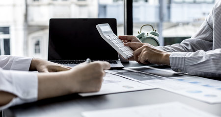 At the meeting room, two businessmen were discussing the joint venture, they were examining the sales report of the sales department to analyze the marketing plan to manage sales. Management concept.の写真素材