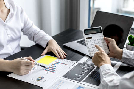 At the meeting room, two businessmen were discussing the joint venture, they were examining the sales report of the sales department to analyze the marketing plan to manage sales. Management concept.の写真素材