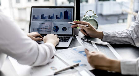 Businesswomen are opening up their laptop's financial information for business partnerships, they...