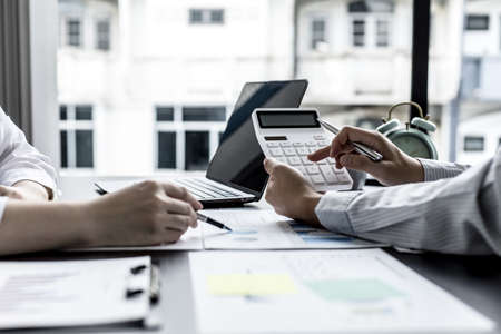 Two businessmen are meeting on corporate finance, a businessman holding a white calculator and...