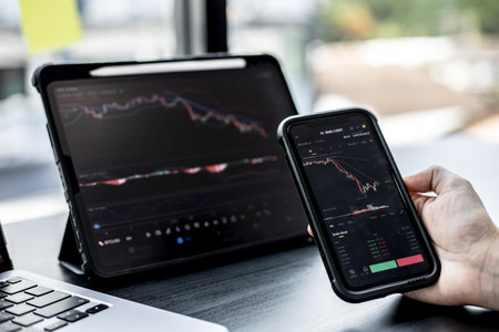 Stock investors hold a phone, open a stock chart viewer to read stock price charts, analyze purchases. Cryptocurrency stocks are popular with both new and old investors. investing in stocks.の写真素材