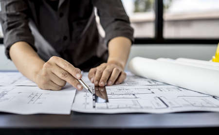 A close-up, an architect, a house designer holding a pen, pointing to a house planの写真素材