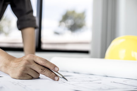 A close-up, an architect, a house designer holding a pen, pointing to a house planの写真素材