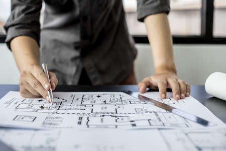 A close-up, an architect, a house designer holding a pen, pointing to a house planの写真素材