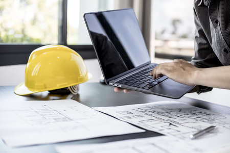 Engineers are typing on a laptop keyboard to review the design of the house