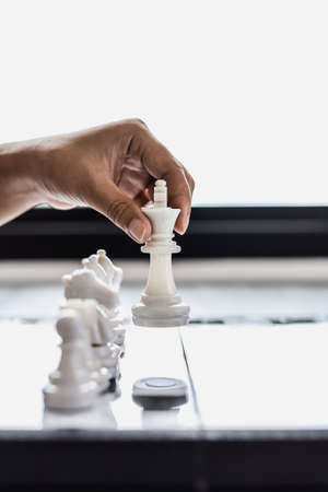 Businesswoman holding white chess pieces on a chessboard