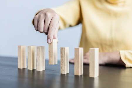 Businesswoman picking up a block of wood from a row