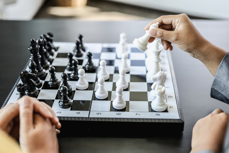 Two business women competitors playing chess board game