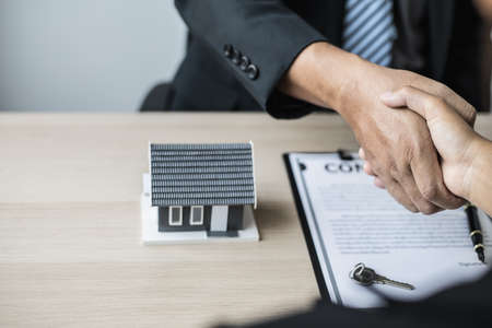 Salesperson and customer shake hands after signing the contract, the salesperson explains the details and informs the customer of the reward. The concept of buying and selling houses.の写真素材