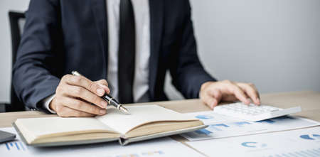 Businessman takes notes on a topic that examines information from finance documents to bring to department and partnership meetings, preparing monthly meeting information. Financial management conceptの写真素材