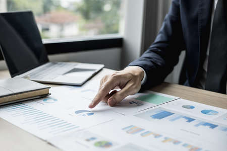 Businessman pointing to a pie chart on the document, he is examining the data from the finance documents to bring in the department and partnership meeting, preparing the monthly meeting information.の写真素材