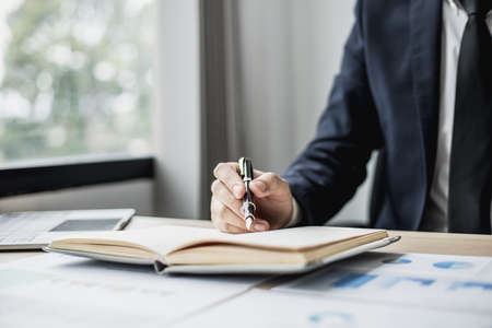 Businessman takes notes on a topic that examines information from finance documents to bring to department and partnership meetings, preparing monthly meeting information. Financial management conceptの写真素材