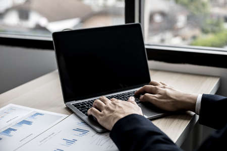 Close-up photo of man hand in suit typing on a laptop keyboard, business man typing chatting with business partner through online messenger. Concept of using technology in communication.の写真素材