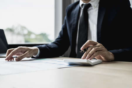 A businessman is reviewing information from finance documents to bring to department and partnership meetings, preparing monthly attendance information. Concept of financial management.の写真素材