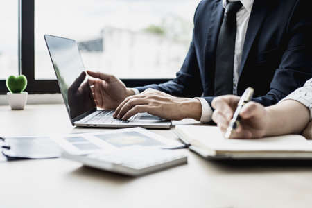 Two staff members of the finance department are sharing monthly financial statements together, they are working on a monthly summary report for their monthly meetings with management.の写真素材