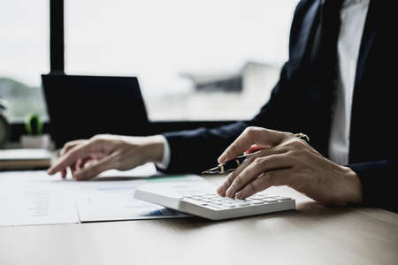 A businessman is reviewing information from finance documents to bring to department and partnership meetings, preparing monthly attendance information. Concept of financial management.の写真素材