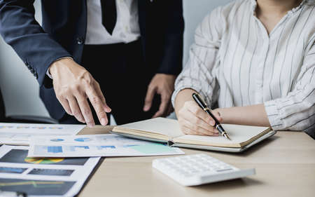 Two businessmen looking at sales data sheets in the office, they are business partners forming a startup company, are having a brainstorming meeting and planning an administration together.の写真素材