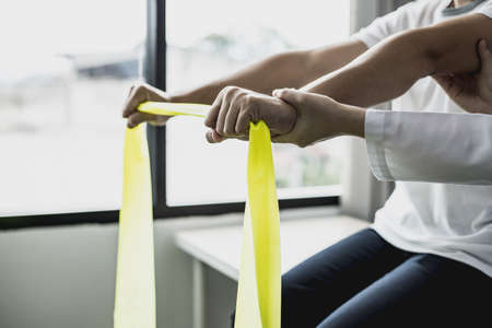 Professional physiotherapists have patients pull the stretch fabric to do physical therapy, most patients are office workers who sit for a long time, causing pain. office syndromeの写真素材