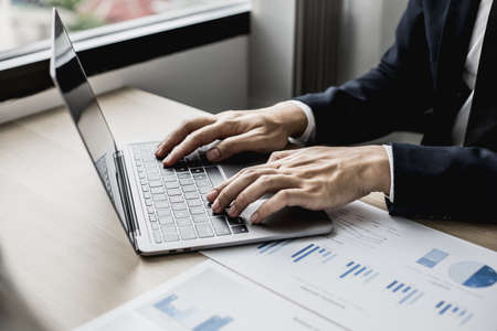 Close-up photo of man hand in suit typing on a laptop keyboard, business man typing chatting with business partner through online messenger. Concept of using technology in communication.の写真素材