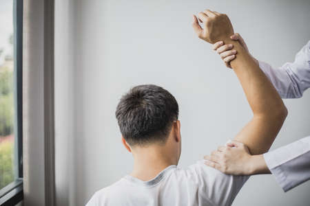 A professional physiotherapist is doing stretching for a patient, the patient has muscle dysfunction due to hard work, most often an office worker who has problems sitting for long periods of time.の写真素材