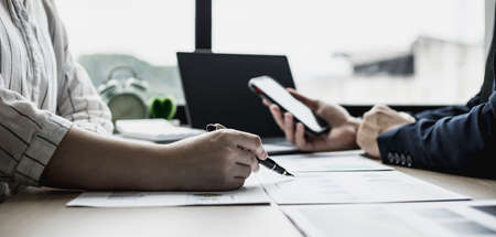 Two businessmen are brainstorming together and reviewing the company financial documents that the finance department has summarized, they are business partners. Business administration concept.の写真素材