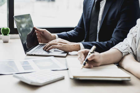 Two staff members of the finance department are sharing monthly financial statements together, they are working on a monthly summary report for their monthly meetings with management.の写真素材