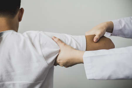 A professional physiotherapist is doing stretching for a patient, the patient has muscle dysfunction due to hard work, most often an office worker who has problems sitting for long periods of time.の写真素材