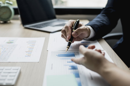 Two businessmen are reviewing monthly sales documents for analysis and marketing plans for more...