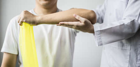 A professional physiotherapist is doing stretching for a patient, the patient has muscle dysfunction due to hard work, most often an office worker who has problems sitting for long periods of time.の写真素材