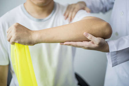 A professional physiotherapist is doing stretching for a patient, the patient has muscle dysfunction due to hard work, most often an office worker who has problems sitting for long periods of time.の写真素材