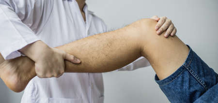 A professional physiotherapist is stretching the patient's legs, the patient has muscle dysfunction due to hard work, most often an office worker who has problems sitting for long periods of time.の写真素材
