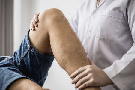 A professional physiotherapist is stretching the patient's legs, the patient has muscle dysfunction due to hard work, most often an office worker who has problems sitting for long periods of time.の写真素材