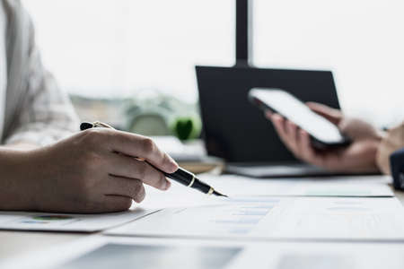 Two businessmen are brainstorming together and reviewing the company financial documents that the...