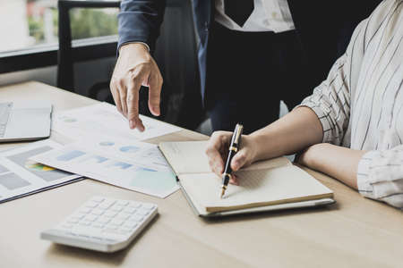 Two businessmen looking at sales data sheets in the office, they are business partners forming a startup company, are having a brainstorming meeting and planning an administration together.の写真素材