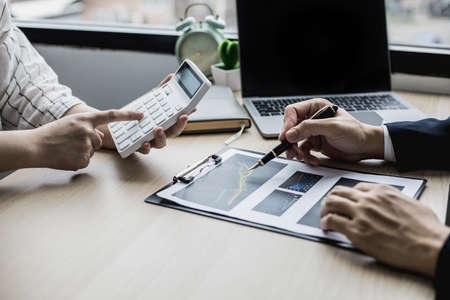 The head of the finance department presents the financial information to the executive, she is pressing the white calculator to calculate the validation number. Concept of financial management.の写真素材
