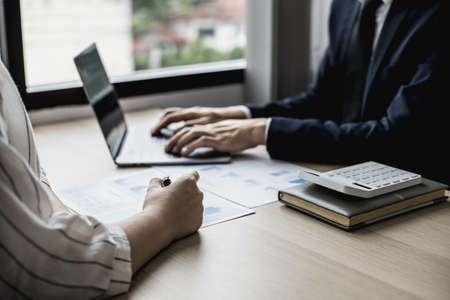 Two staff members of the finance department are sharing monthly financial statements together, they are working on a monthly summary report for their monthly meetings with management.の写真素材