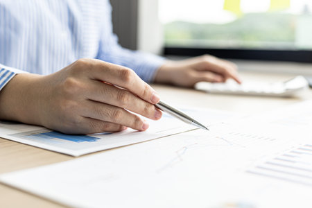 The businesswoman points to the company financial summary prepared by the finance department, she is checking the accuracy of the monthly financial statements. Concept of company financial management.の写真素材