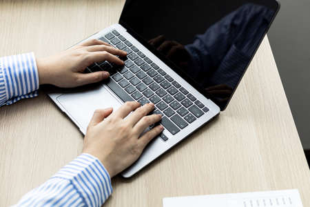 Hands of businesswoman typing on a laptop keyboard, she is using a messaging program to talk to a...