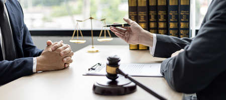 Client was listening to a lawyer advising on an embezzlement case, explaining the details of the proceeding and gathering evidence to file a lawsuit against the defendant. The concept of litigation.の写真素材