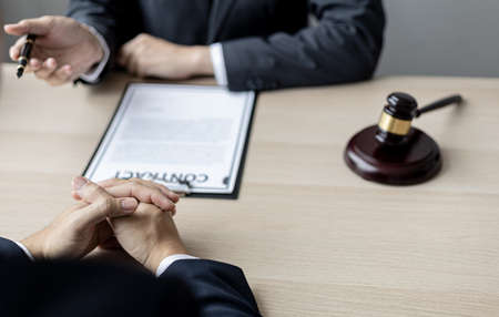 Client was listening to a lawyer advising on an embezzlement case, explaining the details of the proceeding and gathering evidence to file a lawsuit against the defendant. The concept of litigation.の写真素材