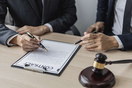 Two male lawyers are consulting together to draft a contract acknowledgment for their clients, they form partnerships to open a law firm. The idea of opening a law firm to accept the lawsuit.の写真素材