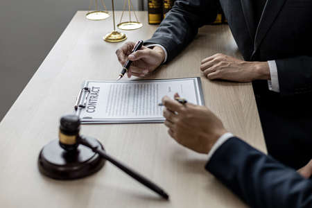 Two male lawyers are consulting together to draft a contract acknowledgment for their clients, they...
