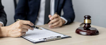 Two male lawyers are consulting together to draft a contract acknowledgment for their clients, they form partnerships to open a law firm. The idea of opening a law firm to accept the lawsuit.の写真素材
